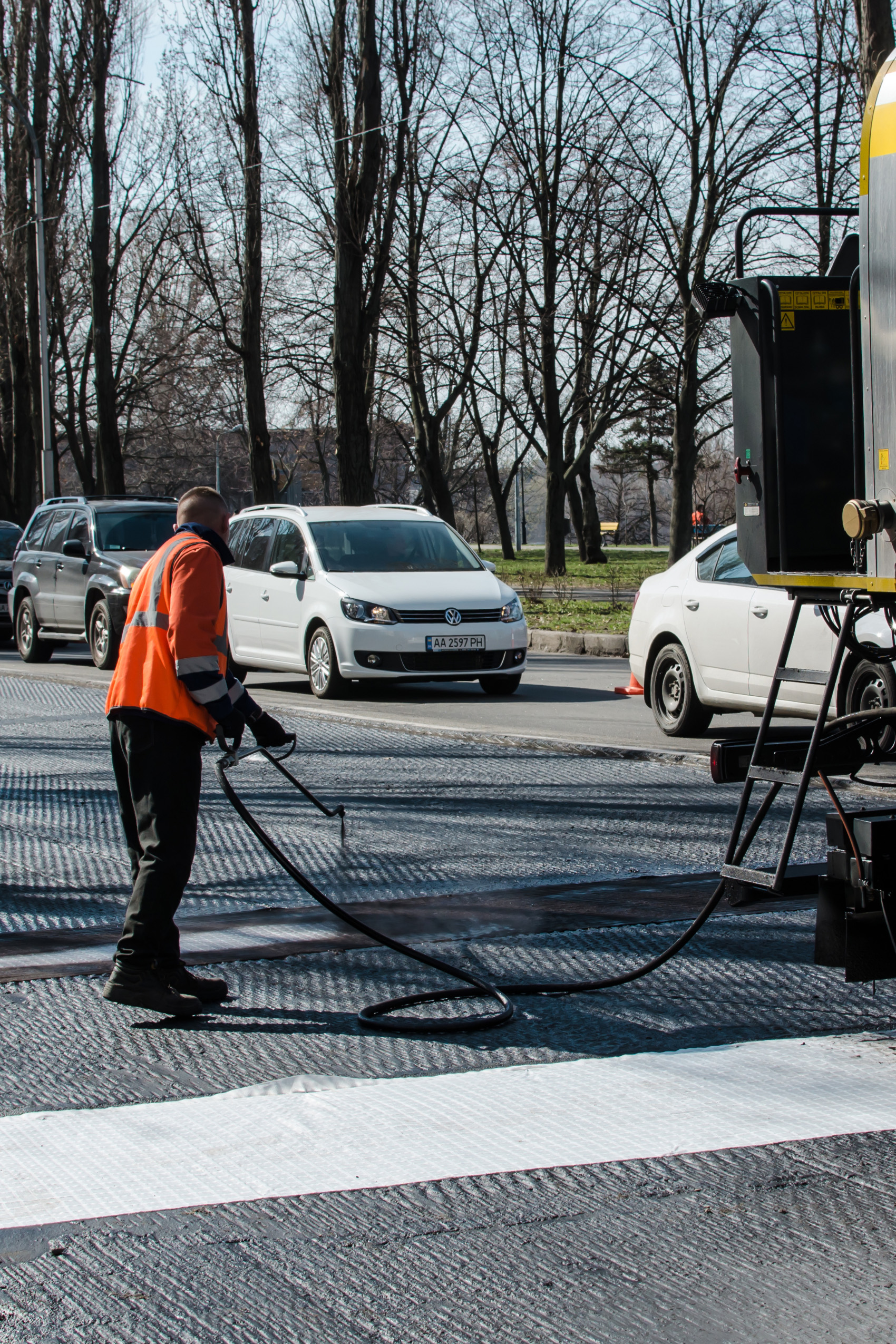 Man spraying sealing coat on asphalt road